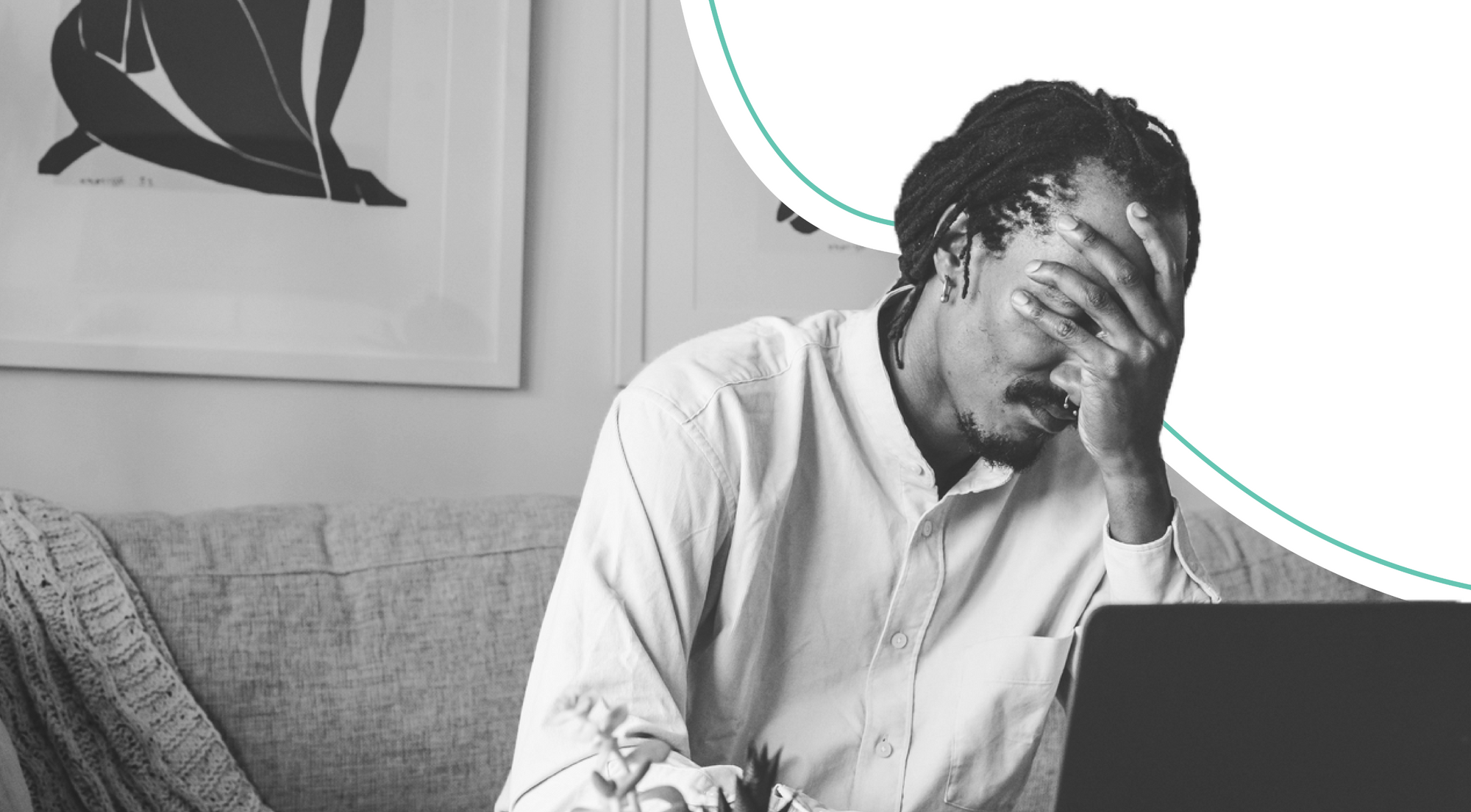 man on coach infront of laptop with head in his hands