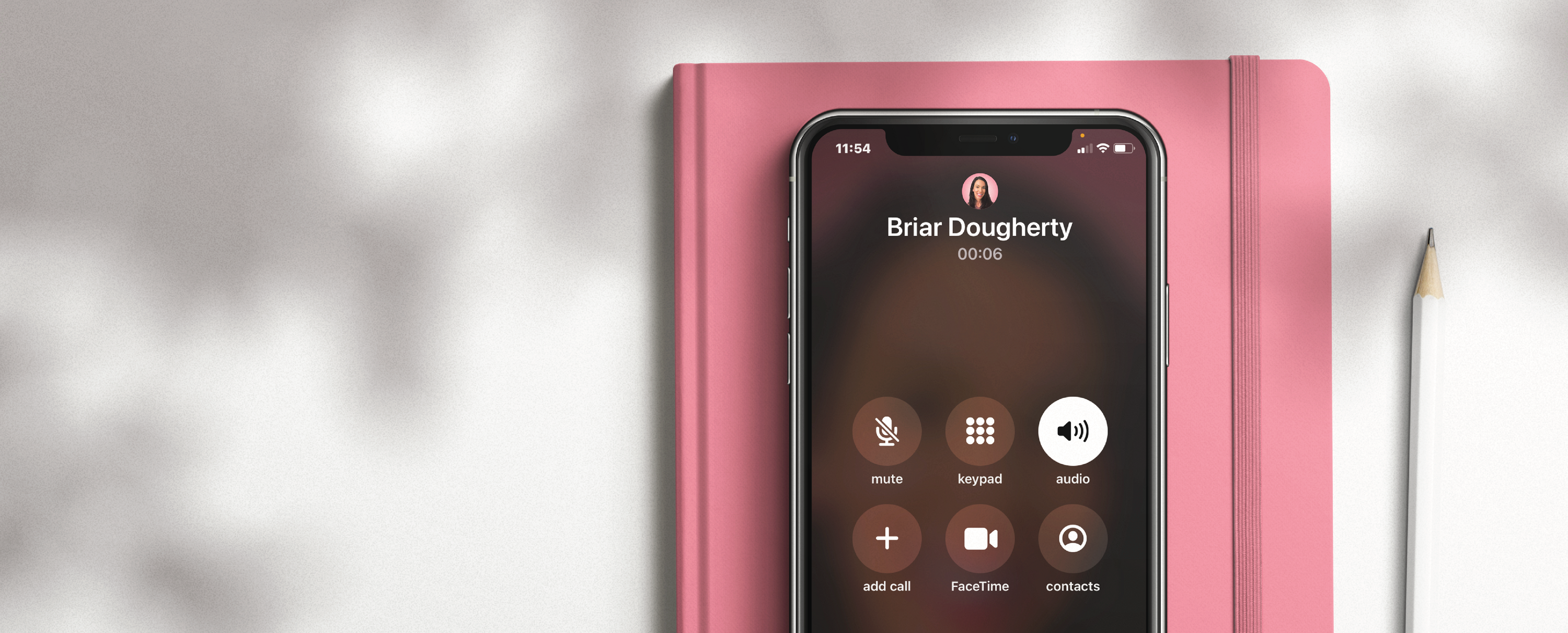 An Iphone on a pink notebook, showing a phone call with CEO Briar.